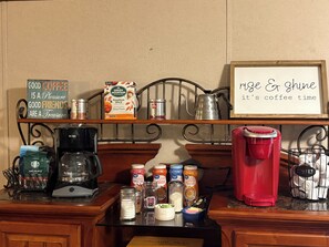 Eine Küchenzeile mit Kaffeemaschine und Zubehör, ein Schild mit der Aufschrift 'nice & shine it's coffee time' sowie verschiedene Kaffeeartikel.