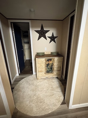 Un pasillo con un aparador de madera, dos adornos de estrella en la pared y una alfombra mullida.