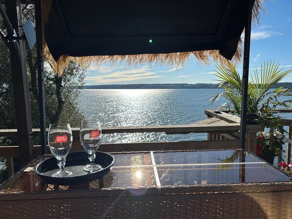Une table avec deux verres et un plateau, donnant sur une étendue d’eau.