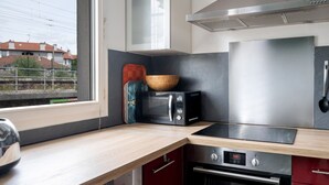A modern kitchen with a microwave, oven, and stainless steel appliances. - Appartement Crista - Welkeys (Saint-Denis)