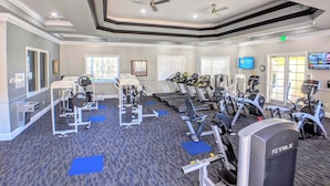 A gym with treadmills, weight machines, and a ceiling fan.
