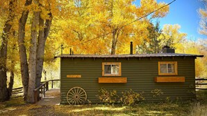 A rustic cabin with a wooden wheel, a small porch, and a sign indicating it is a park facility. - TATA River Cabins- group getaway (Salida)