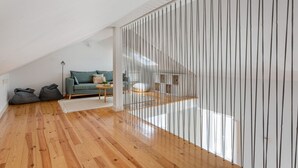 En modern loftlägenhet med trägolv, en grön soffa och en trappa med ett metallräcke.