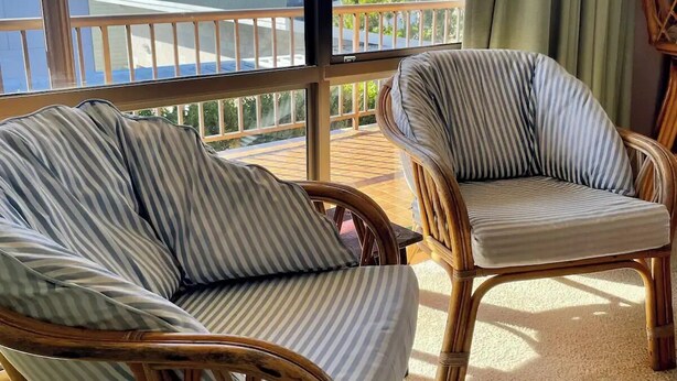 Een balkon met rieten stoelen en uitzicht op de oceaan.