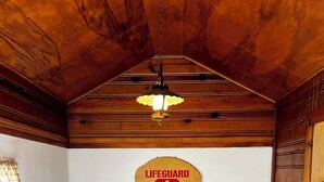 A room with a grey sofa, a wooden ceiling, and a lifeguard sign on the wall. - Lake front updated cabin-close to everything!! (Ashtabula)