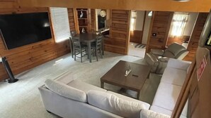 A cozy living room with a large sofa, a coffee table, and a dining area with chairs and a small table. - Lake front updated cabin-close to everything!! (Ashtabula)