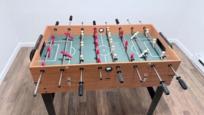 A foosball table with a wooden frame, metal rods, and red and white balls. - The Romantic Getaway W/Fireplace-Grill-Fire pit-walkable distance to the Lake! (Pocono Lake)