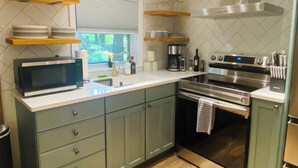 A modern kitchen with a built-in microwave, stainless steel appliances, and wooden shelves. - The Romantic Getaway W/Fireplace-Grill-Fire pit-walkable distance to the Lake! (Pocono Lake)