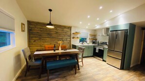 A modern kitchen with a dining area, wooden wall, and built-in appliances. - The Romantic Getaway W/Fireplace-Grill-Fire pit-walkable distance to the Lake! (Pocono Lake)