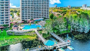 A hotel with a pool, dock, and surrounding greenery.