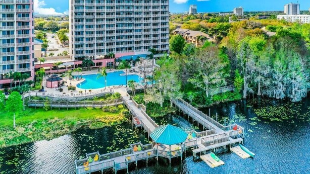 A hotel with a pool, dock, and surrounding greenery.