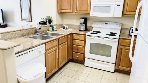 A kitchen with wooden cabinets, a white stove, a microwave, and a dishwasher.