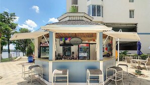 A small outdoor bar with a counter, stools, and a menu board.