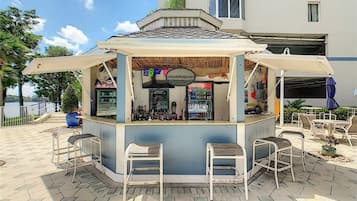 Een klein buitengebied met een bar, krukken en een menubord.