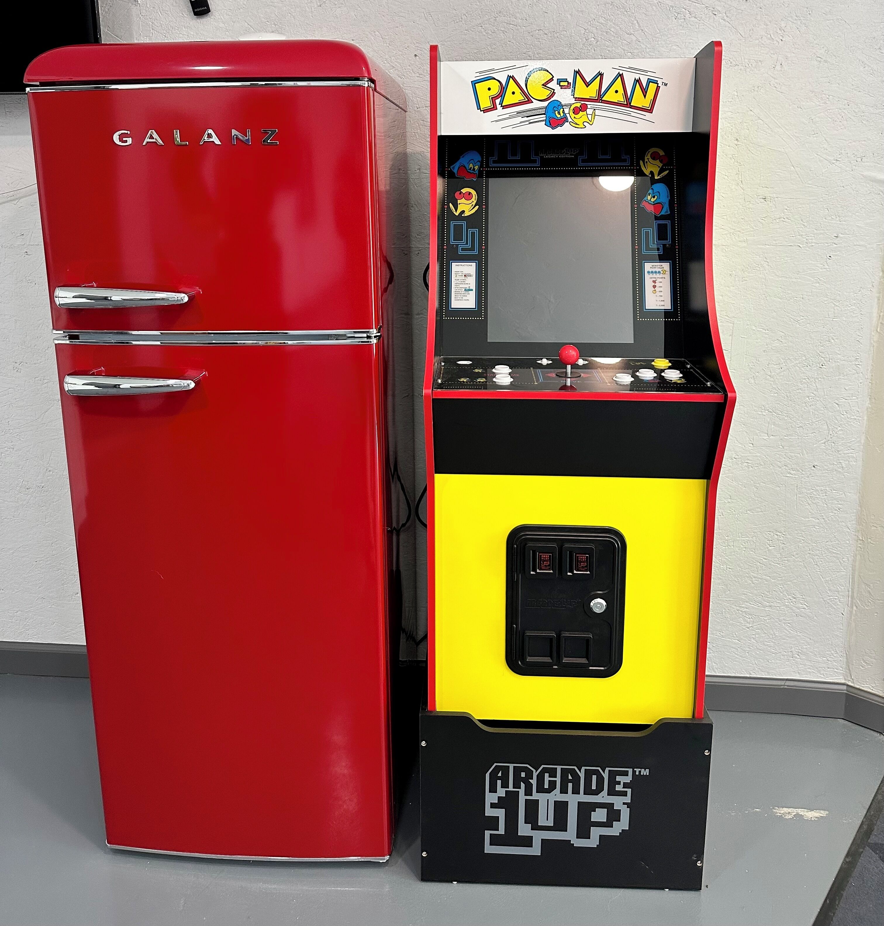 A red Galanz refrigerator and a black and yellow arcade machine with Pac-Man and other characters.