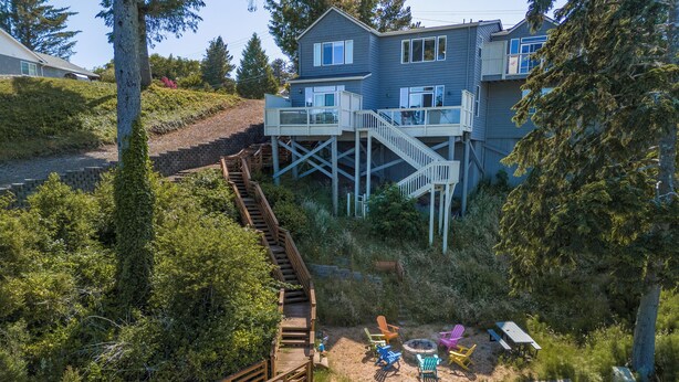 A two-story house with a wooden deck and a staircase leading to a balcony. - Lakefront Townhome with Dock on Devils Lake (Lincoln City)