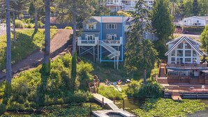 A lakeside property with a dock, a house with a deck, and a boat. - Lakefront Townhome with Dock on Devils Lake (Lincoln City)