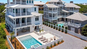 Ein großes, mehrstöckiges Wohnhaus mit Swimmingpool, mehreren Balkonen und einer überdachten Terrasse.
