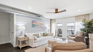 A modern living room with a white sofa, beige armchairs, a coffee table, and a ceiling fan. - Shoreline Breeze | Steps to the Beach | Beautiful views from 2nd and 3rd balconies (Inlet Beach)