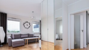 Moderni olohuone, jossa on sohva, pieni pöytä ja suuri peili.