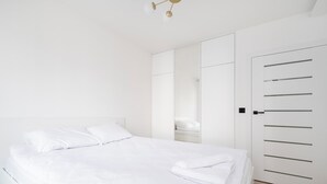 Une chambre à coucher moderne avec un grand lit, une armoire et un miroir.