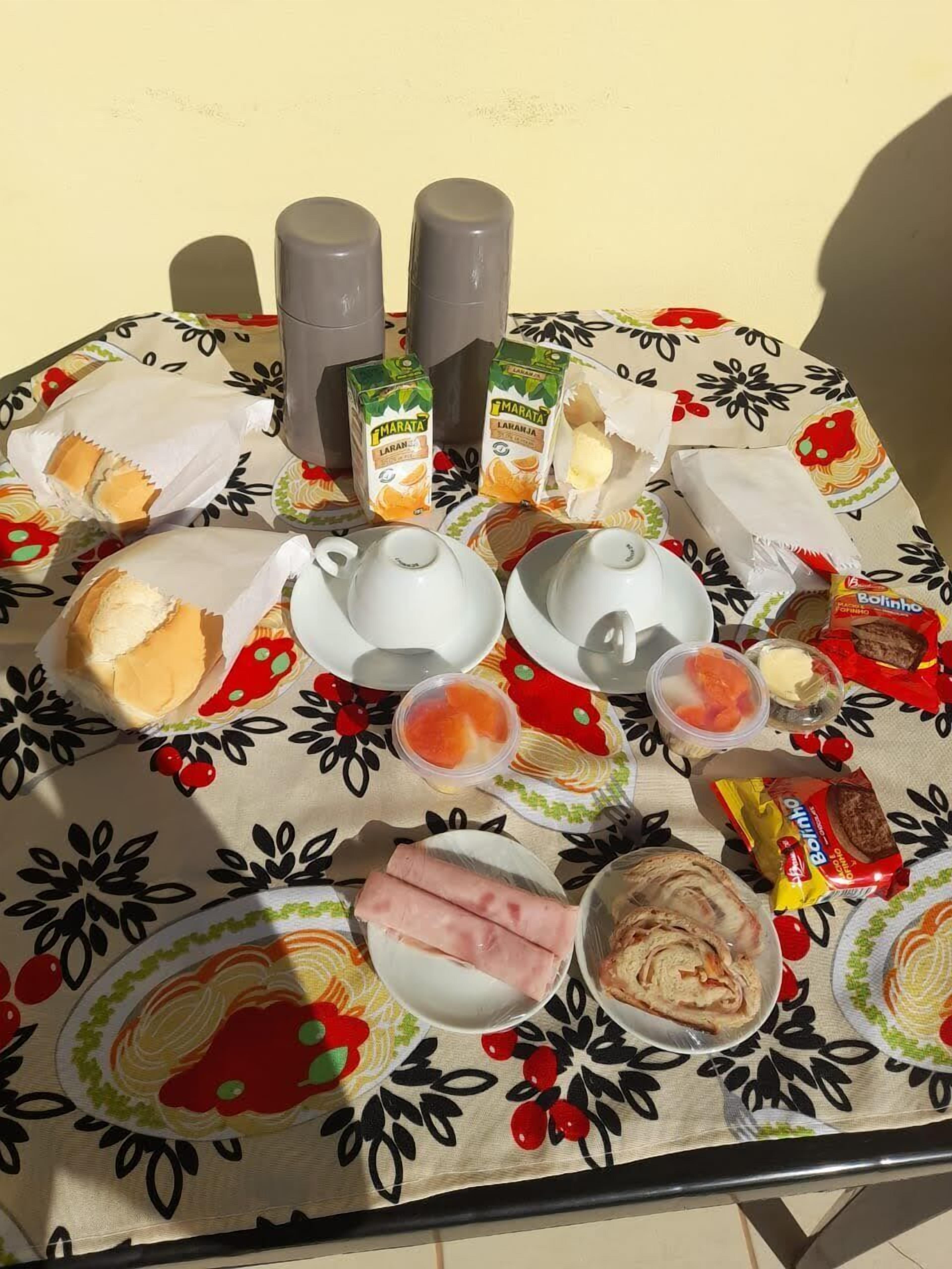 Una mesa dispuesta con diversos alimentos, como pan, pasteles y salsas, sobre un mantel con estampado floral.