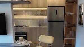 Una cocina moderna con refrigerador integrado, un comedor con una mesa redonda y una silla, y una pequeña alfombra en el suelo.