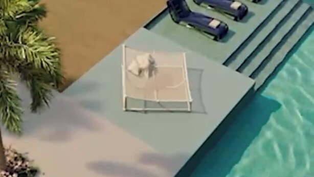 Un área de piscina con un sillón de sol y sillones reclinables, una palmera y una pequeña terraza.