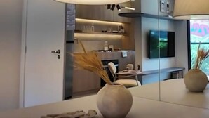 Una cocina moderna con una amplia mesa de comedor, dos lámparas colgantes y un florero con plantas secas.
