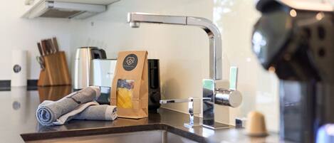 A modern kitchen with a stainless steel sink, a coffee machine, and a paper bag on the counter.