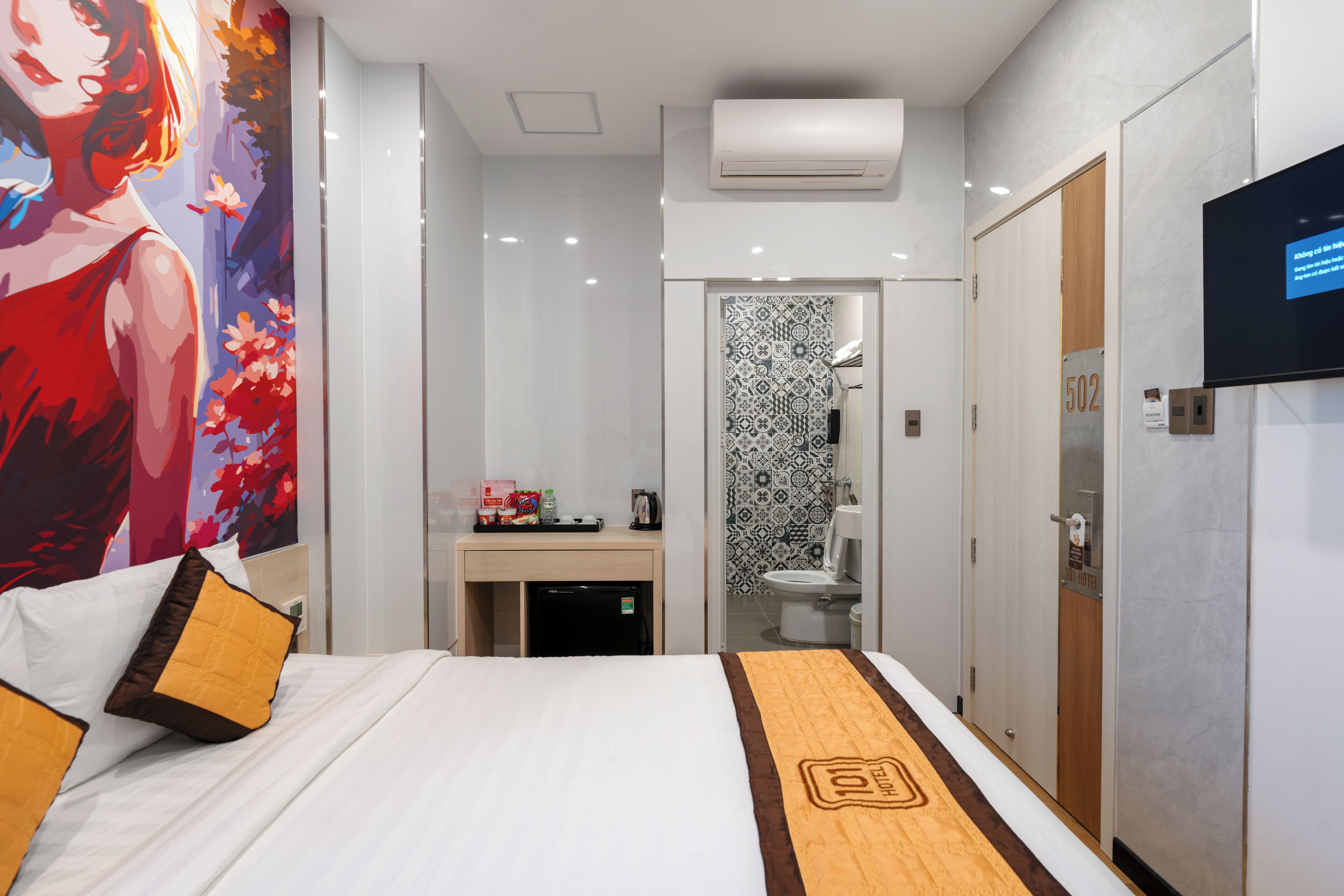 A hotel room with a bed, a desk, a TV, and a bathroom.