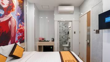 A hotel room with a bed, a desk, a TV, and a bathroom.