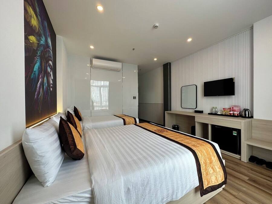 Habitación de hotel con una cama grande, un escritorio, un televisor y un espejo.