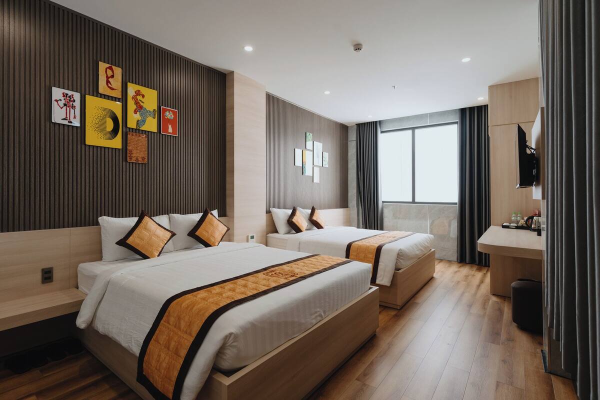 A modern hotel room with two beds, a desk, and a large window.
