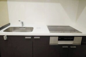 Een koelkast, een magnetron, een kookplaat, kookgerei, borden en bestek