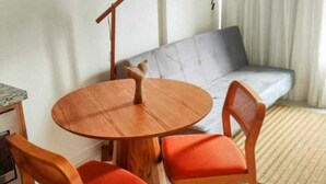 Un coin repas comprenant une table ronde en bois et deux chaises, un canapé et une lampe sur pied.