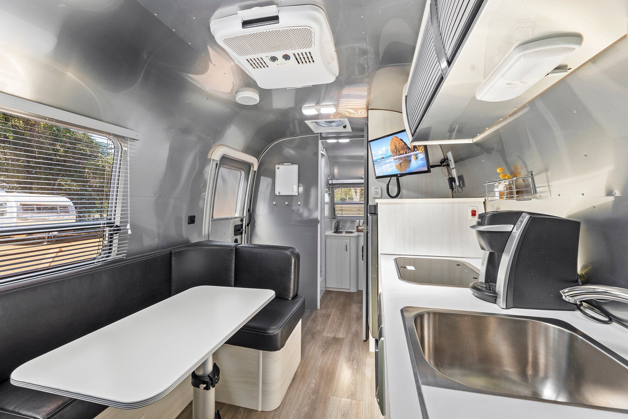 Un intérieur de camping-car compact comprenant un coin cuisine, un espace salon et un écran de télévision.