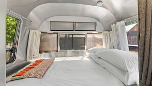 A bedroom with a bed, curtains, and a window.