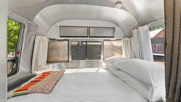 A bedroom with a bed, curtains, and a window.