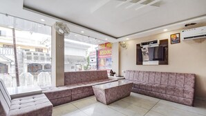 A hotel lobby with a large sectional sofa, a coffee table, and a TV mounted on the wall. - Fabexpress Park Residency I (Haridwar)