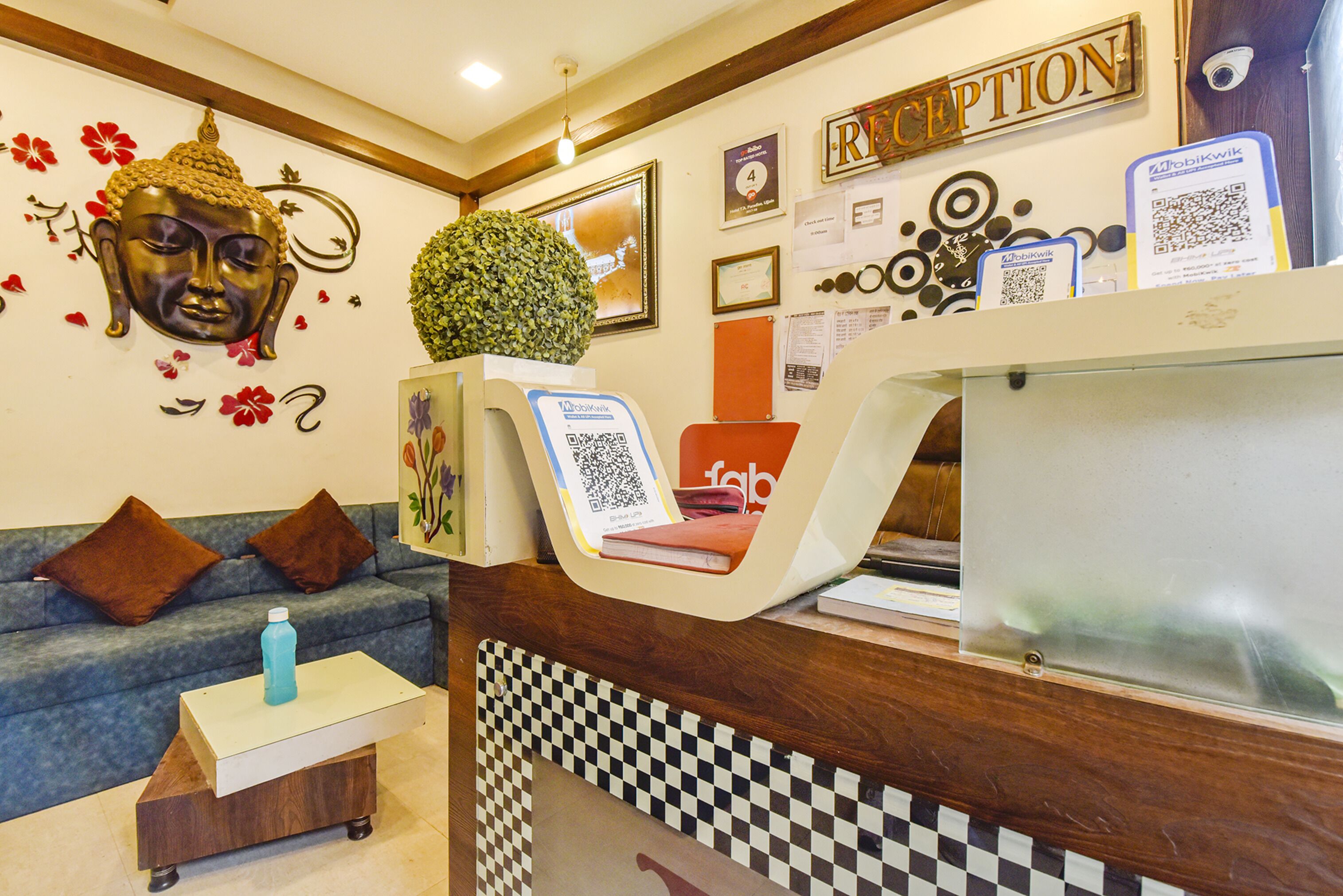 A reception area with a Buddha head decoration, a reception desk, a blue sofa, and a small table with a water bottle.