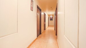 Ein Hotelgang mit Türen an beiden Seiten, gefliestem Boden und einer hellen Wand.