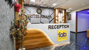 A reception area with a marble wall, a wooden reception desk, and a clock.