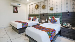 A hotel room with two beds, a marble-tiled floor, a decorative wall with a clock, and a small table with amenities.