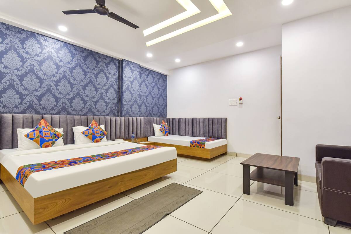 A modern bedroom with two beds, a ceiling fan, recessed lighting, and a small table.