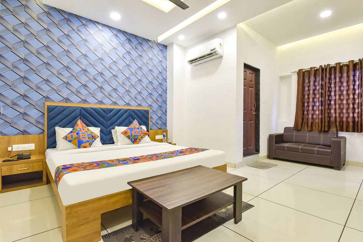 A hotel room with a bed, bedside table, and a sofa.