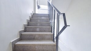 A staircase with granite steps and black metal railings, leading to a landing with a patterned window. - Treebo Bella Vista (Udaipur)