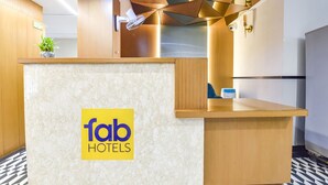 A reception desk with a 'fab hotels' logo, a potted plant, and a modern geometric ceiling design. - Treebo Bella Vista (Udaipur)