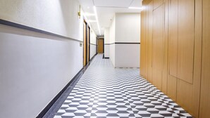 A hallway with a checkered floor pattern, wooden paneling on one side, and a door at the end. - Treebo Bella Vista (Udaipur)