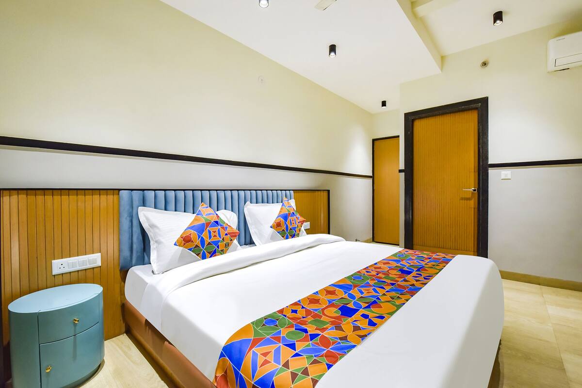 A hotel room with a bed, a nightstand, a wooden headboard, and a door.